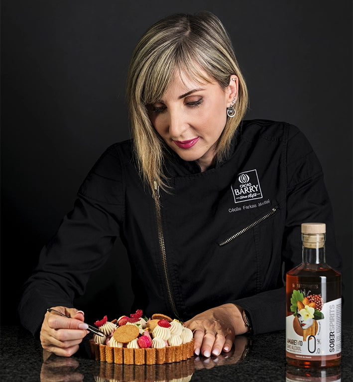 Photographie sur fond noir de Cécile Moritel préparant la Tarte Amanda By Cécile Moritel, préparé avec du Sober Spirits Amaretto 0.0% d'alcool présent à côté d'elle.
